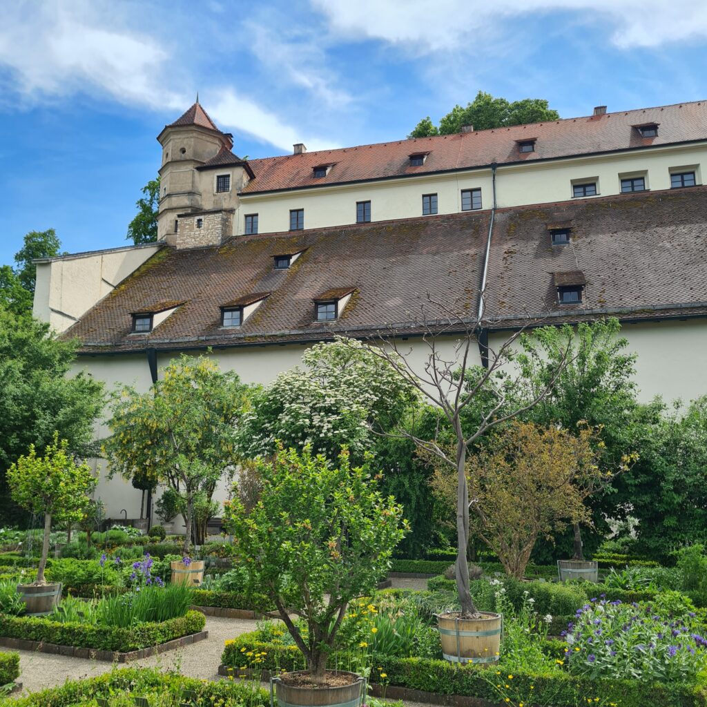 Image of the Bastionsgarden Eichstätt. You can see the flowerbeds in front of the castle wall. It is summer and the garden is green.